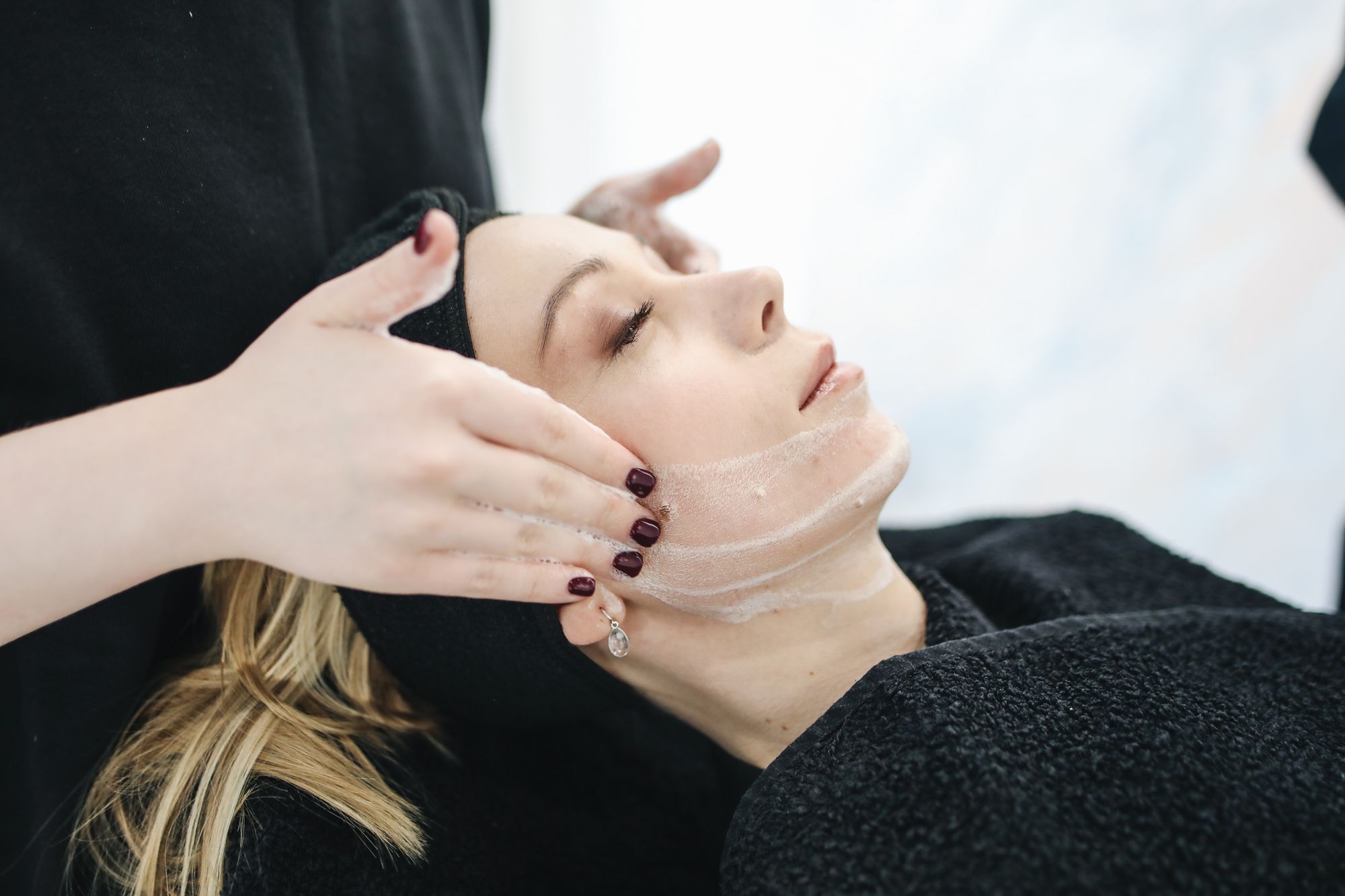 Practitioner performing a smoothing treatment along a client's jawline.
