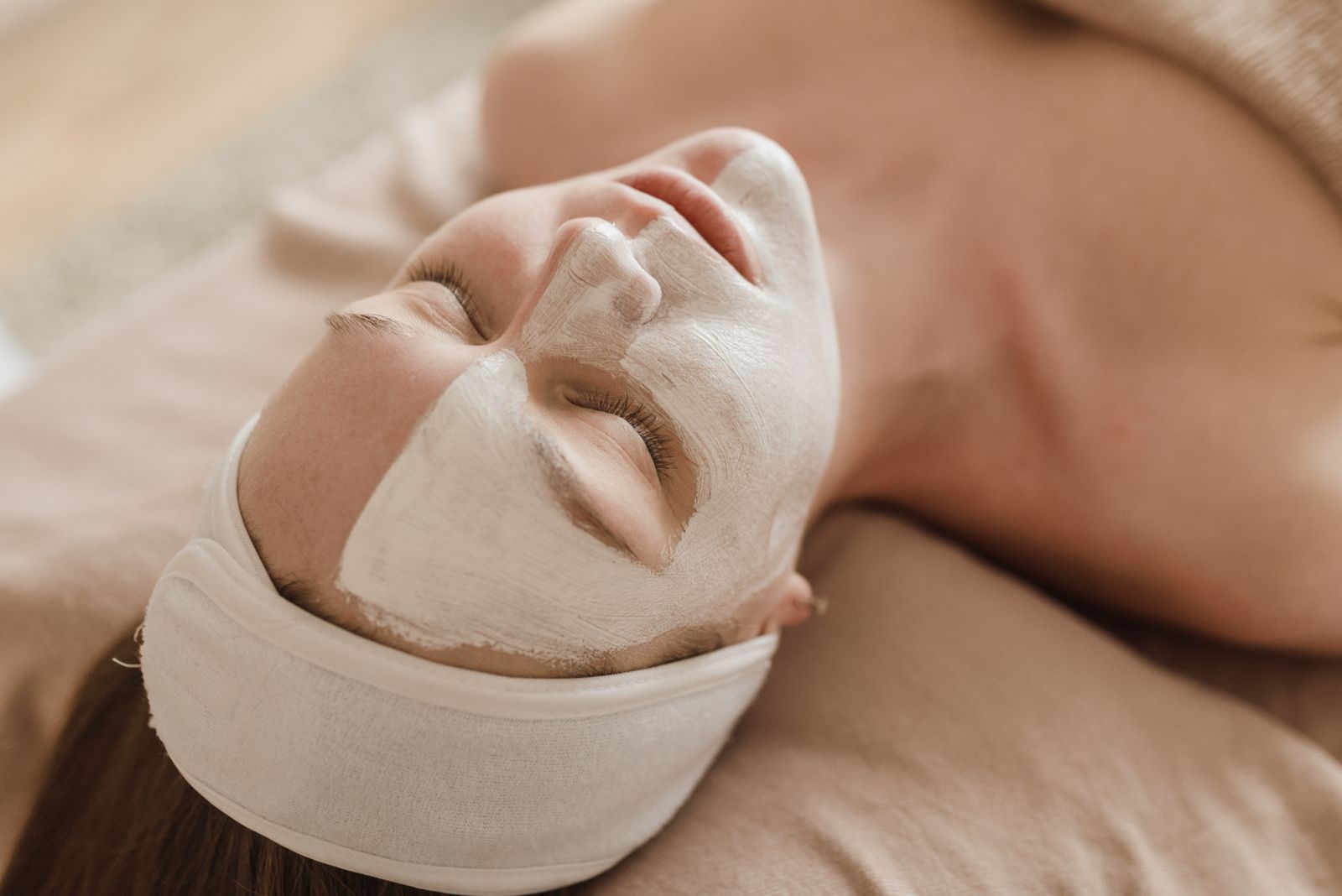 A treatment mask being worn during a facial, the client resting with eyes closed.